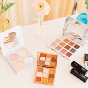 Aesthetic display of makeup palettes and lipsticks surrounded by flowers.